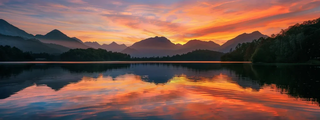 a breathtaking sunset casts vibrant hues of orange and pink across a tranquil lake, reflecting the serene silhouettes of towering mountains in the distance.